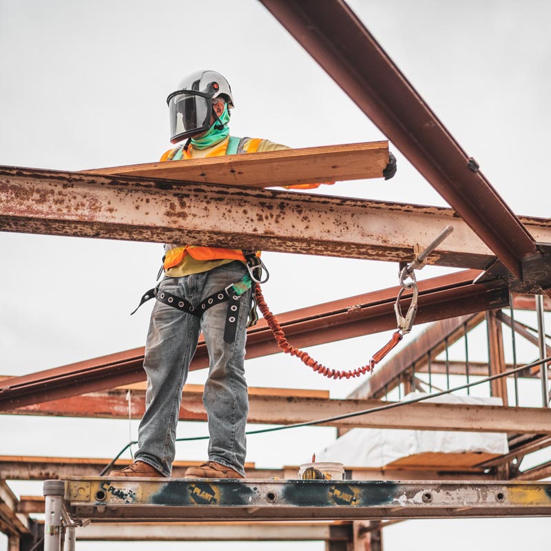 Man wearing protective gear standing on scaffolding and building a steel roof frame