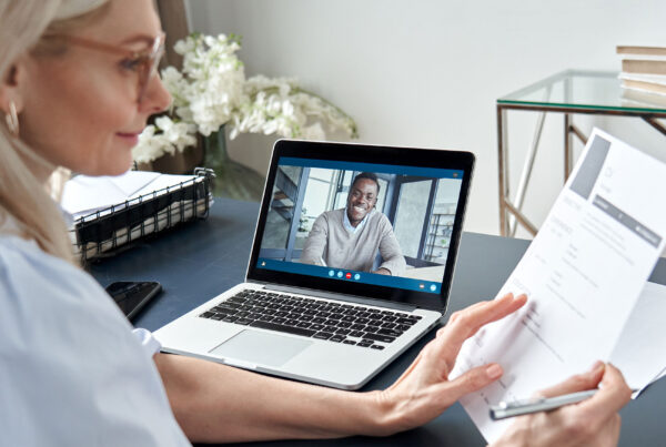 Woman reading a piece of paper while on a video call with a colleague