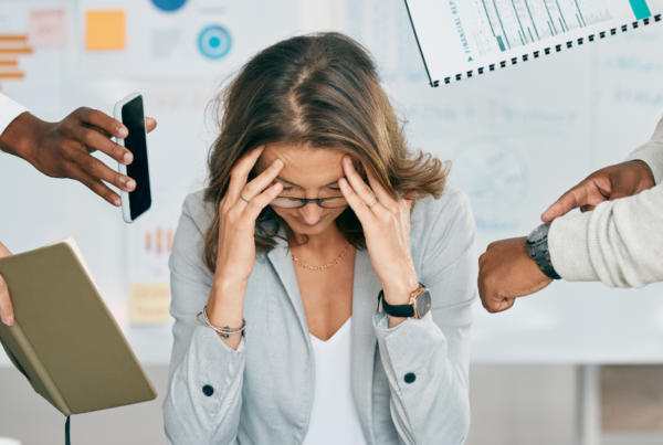Woman with head in hands looking stressed about her mental health and the recruitment tasks around her