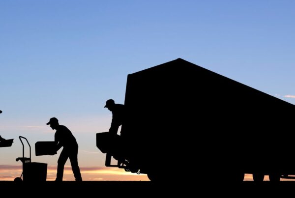 3 people unpacking a moving truck in front of a sunset