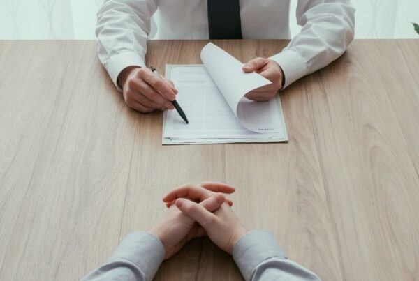 Two people sitting at a desk, one is being intervied by the other